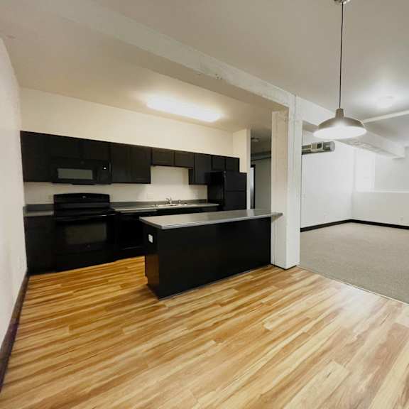 a kitchen with black cabinets and a wooden floor.