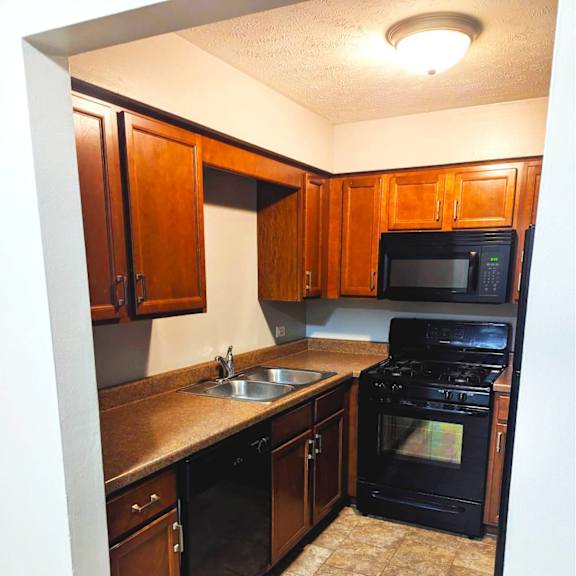 a kitchen with black appliances and brown cabinets.