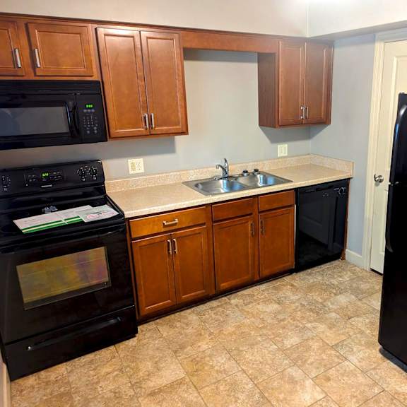 a kitchen with black appliances and wooden cabinets.