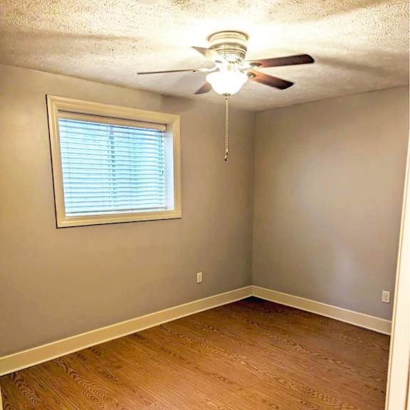 a room with a ceiling fan and a window with blinds.
