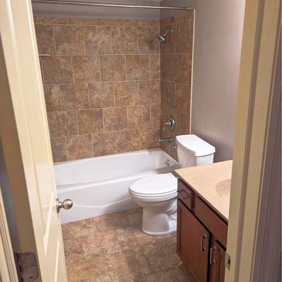 a bathroom with a toilet, sink, and tiled shower.