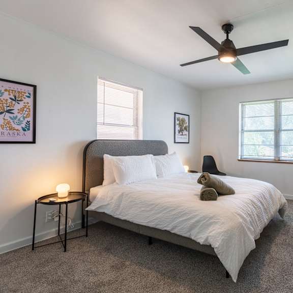 a bedroom with a bed, a ceiling fan, and a television.