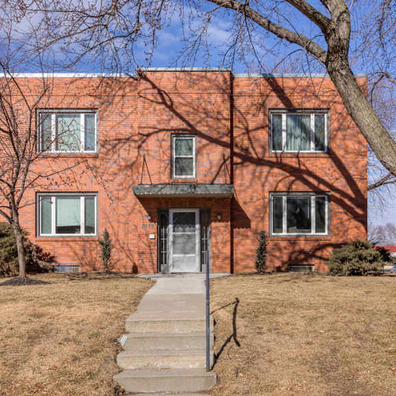 a red brick house with a grey door and steps leading up to it.