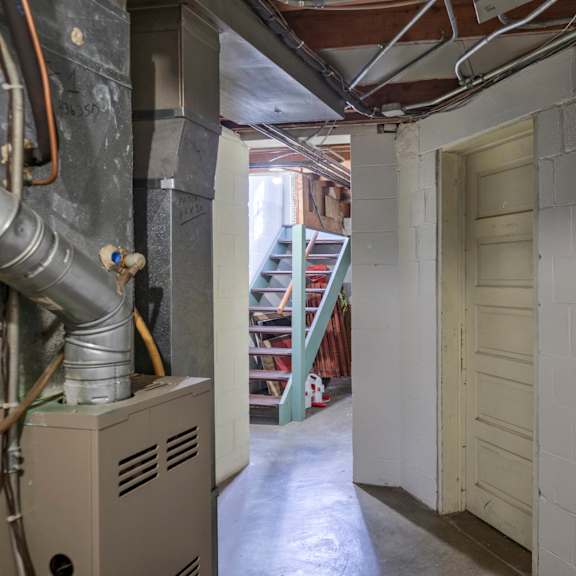 a long hallway with a door on the right and a furnace on the left.