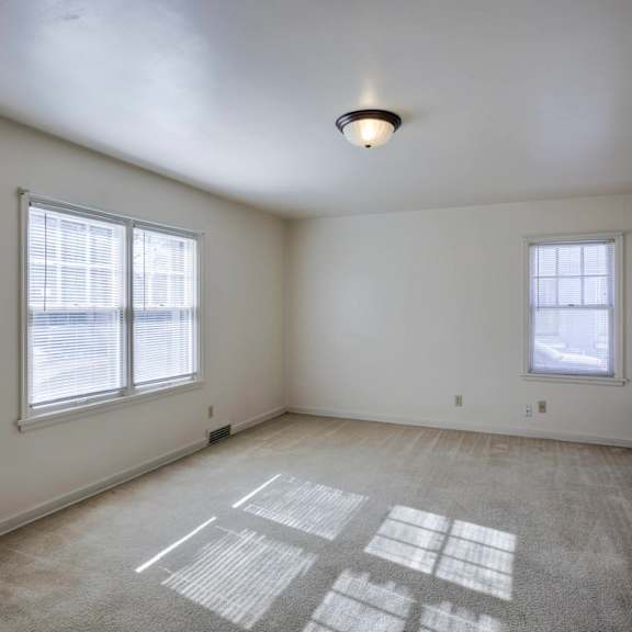 a room with two windows and a carpet on the floor.