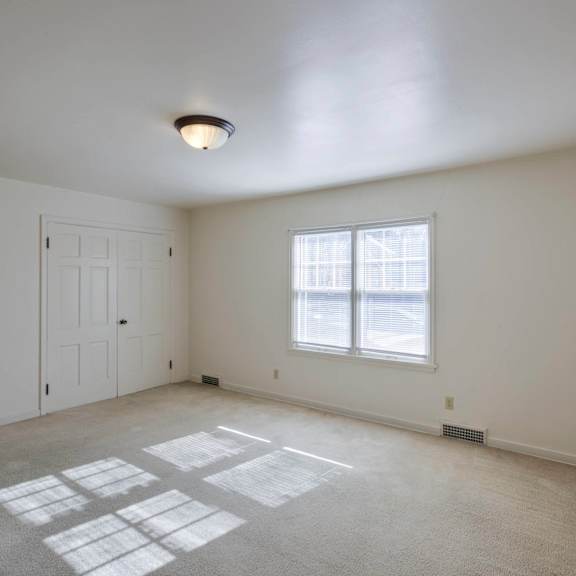 a room with white walls and a window with blinds.