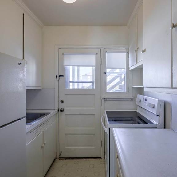 a white kitchen with a fridge, oven and sink.