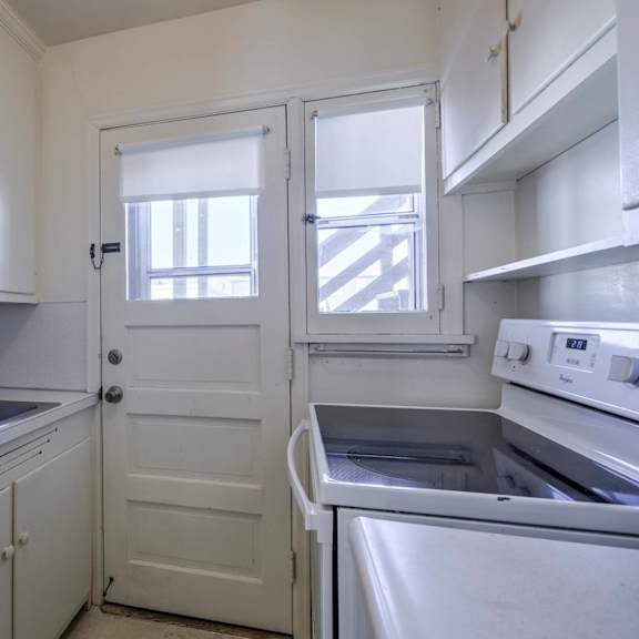 a white kitchen with a refrigerator, sink, and stove.