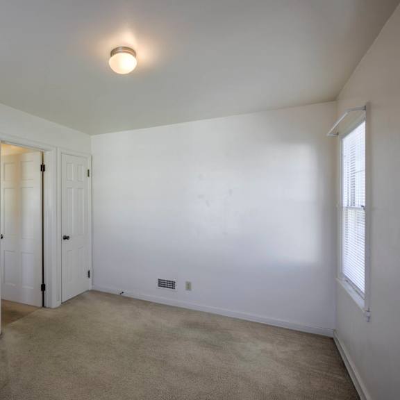 a room with a white door and a window on the right side.
