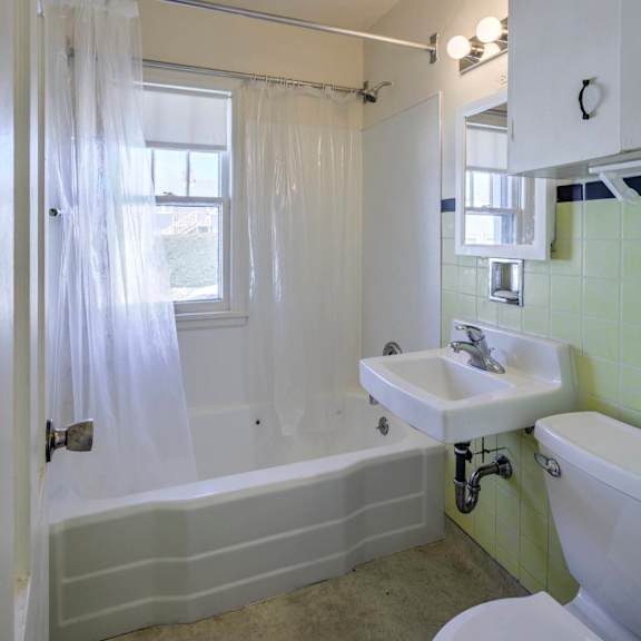a white bathroom with a green wall and a white toilet.