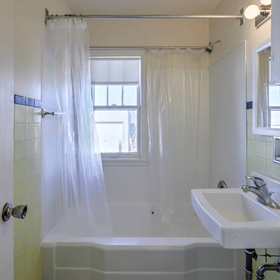 a white bathroom with a tub, sink and shower.