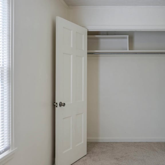 a white closet with a shelf and a door.