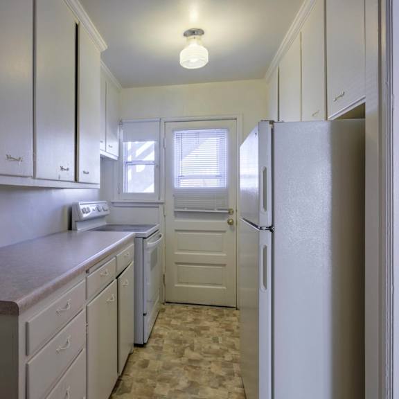 a kitchen with white cabinets and a refrigerator.