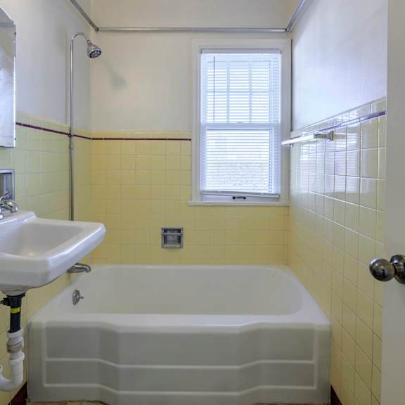 a white sink is on the left side of a bathtub in a bathroom.
