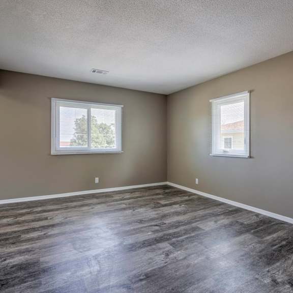 a room with wooden flooring and two windows.