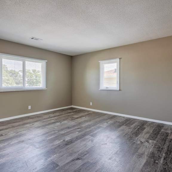 a room with wooden flooring and two windows.