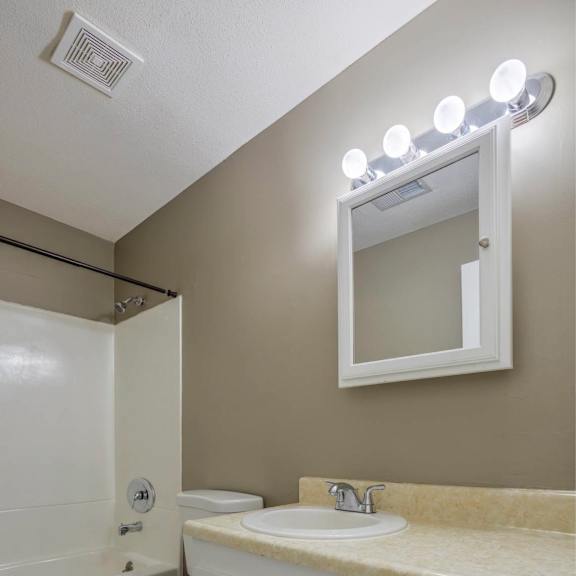 a bathroom with a toilet, sink, and mirror.