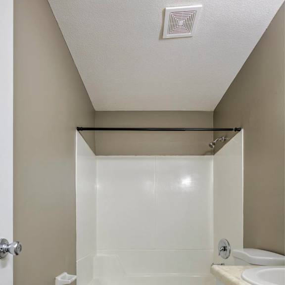 a white toilet sits next to a bathtub in a small bathroom.