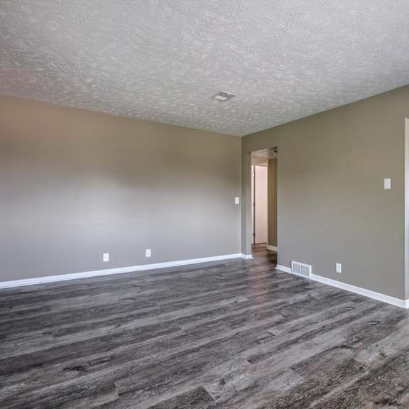 a kitchen area with a refrigerator, microwave, and cabinets.