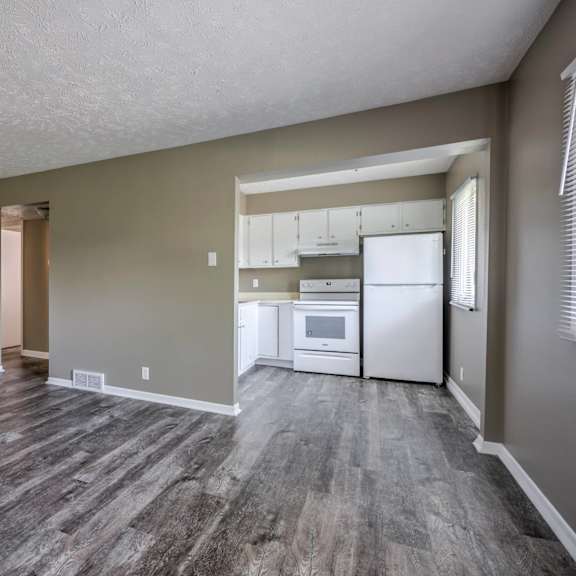 a kitchen with a refrigerator, microwave, and oven is visible through a doorway.