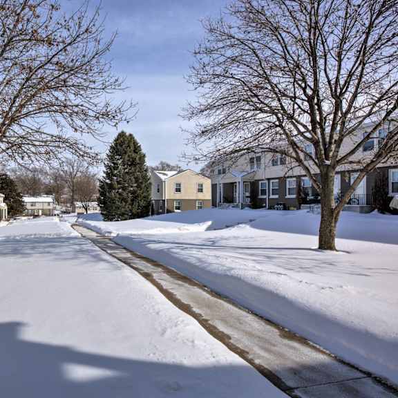 a snowy street with houses on either side and bare trees.