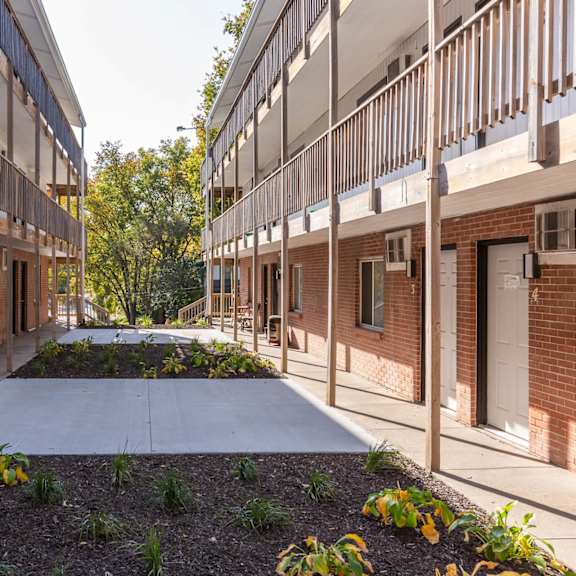 a long, narrow courtyard between two rows of red brick buildings with white doors.