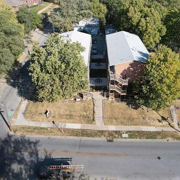 a large building with a grey roof is surrounded by trees.