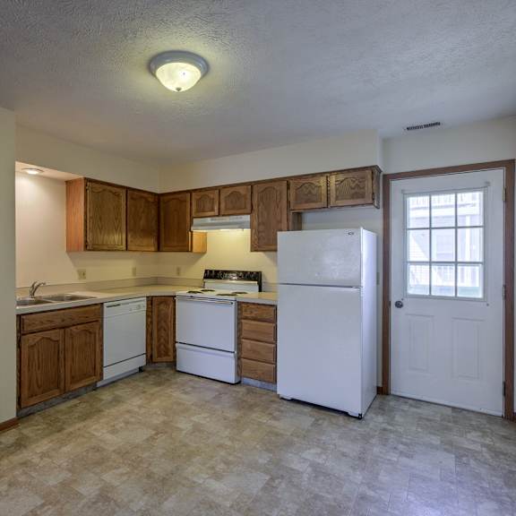 a kitchen with white appliances and wooden cabinets.
