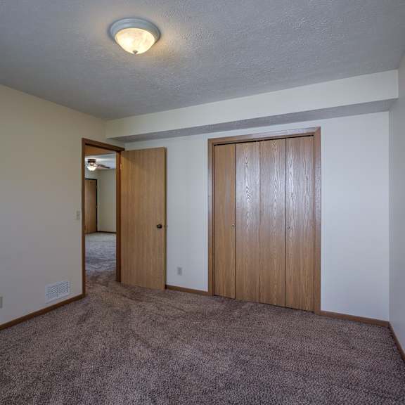 a room with a carpeted floor and two wooden doors.