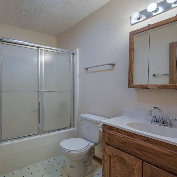 a bathroom with a toilet, sink, and shower.