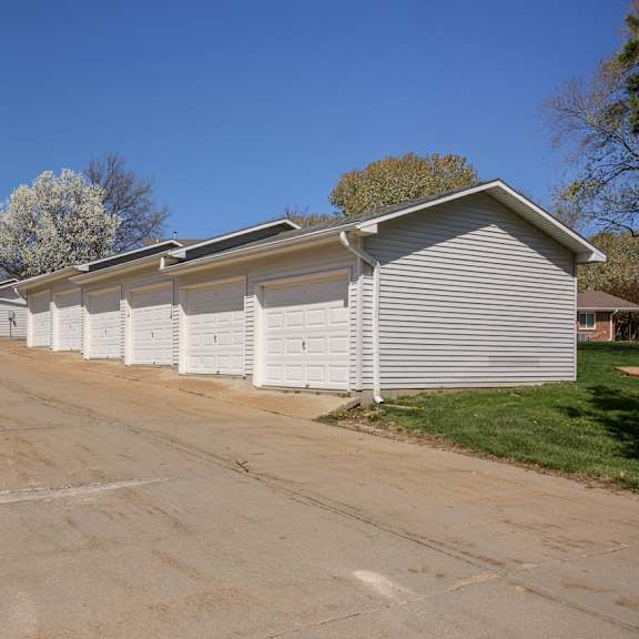 a long white garage with a driveway in front of it.
