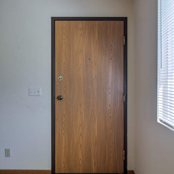 a brown wooden door is closed and has a handle and a lock.