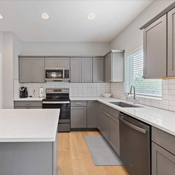 a modern kitchen with a white countertop and stainless steel appliances.