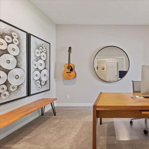 a room with a wooden desk and a guitar hanging on the wall.