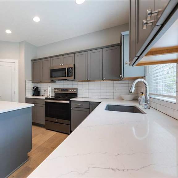 a modern kitchen with a white countertop and dark brown cabinets.