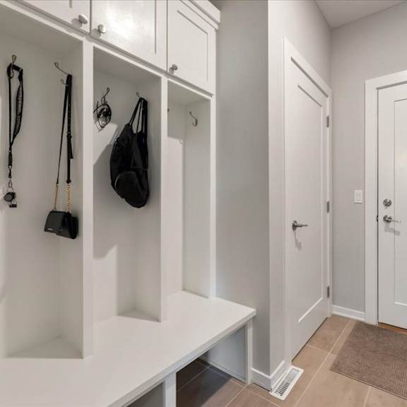 a hallway with a bench and a coat rack.