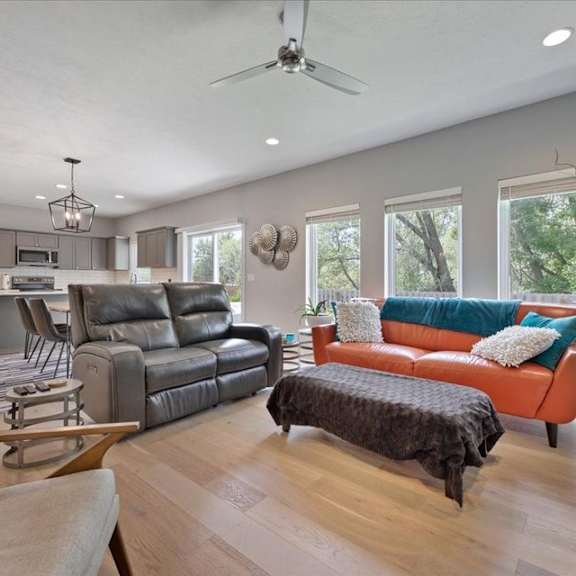 a modern living room with a grey sofa and a brown ottoman.