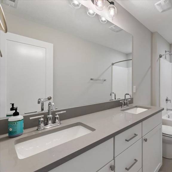 a white bathroom with a sink, mirror, toilet, and bathtub.