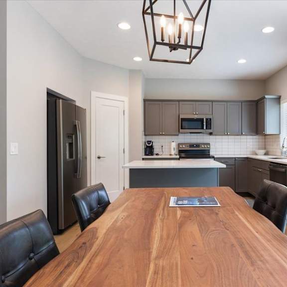 a modern kitchen with a wooden table and black leather chairs.