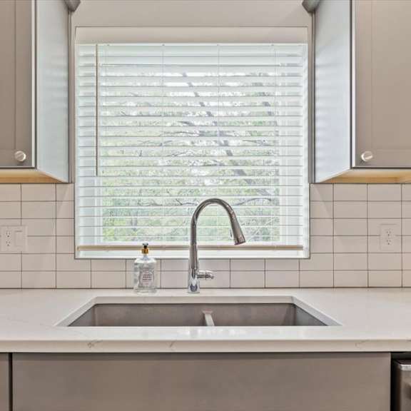 a kitchen with a sink and a window with blinds.