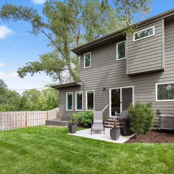 a grey house with a wooden fence and a green lawn.