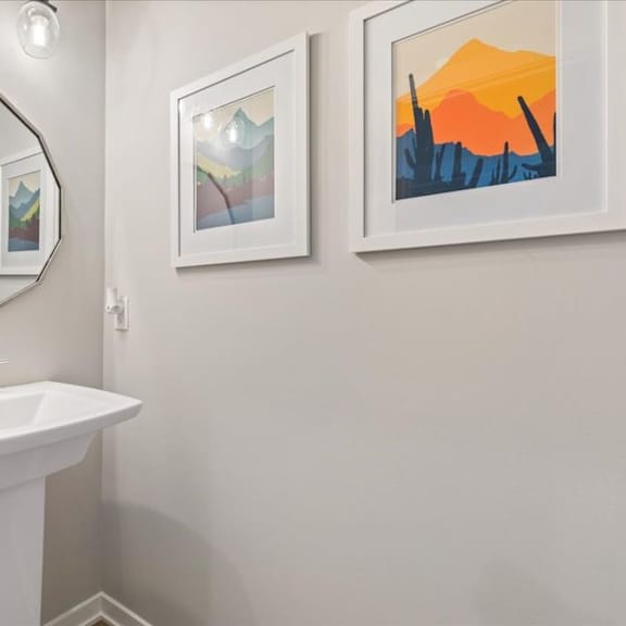 a bathroom with a white sink and two framed pictures on the wall.