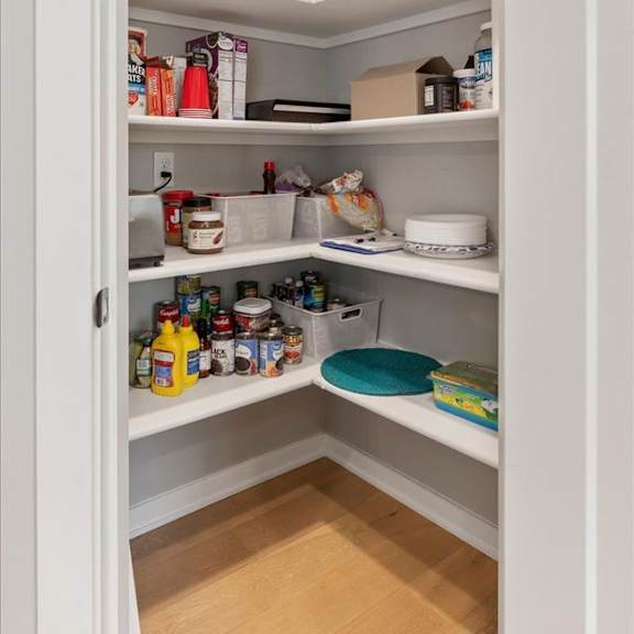 a white pantry with food and kitchen supplies on the shelves.