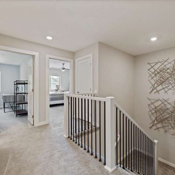a hallway with a staircase and a wall art.