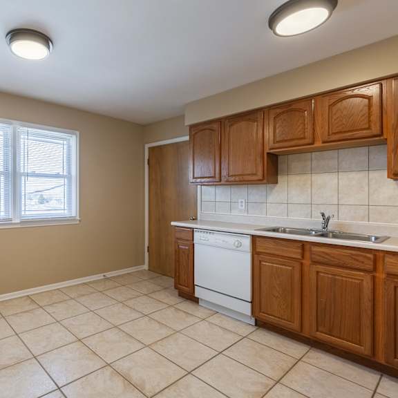 a kitchen with a white dishwasher and wooden cabinets.
