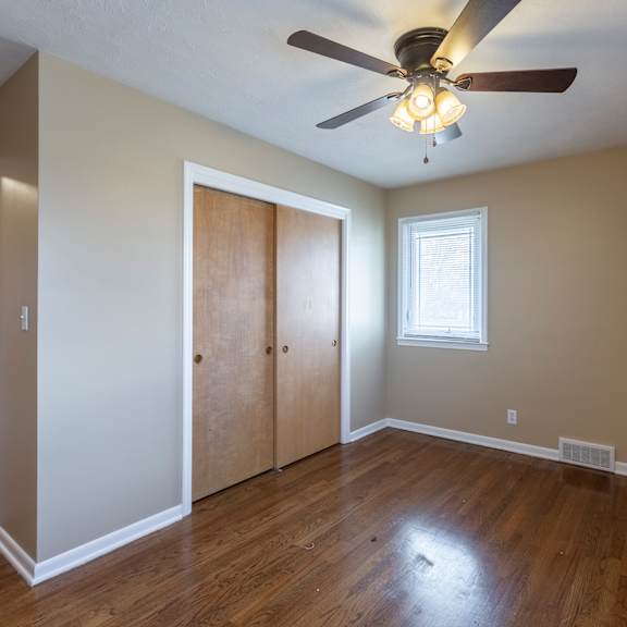 a room with a ceiling fan and wooden floors.