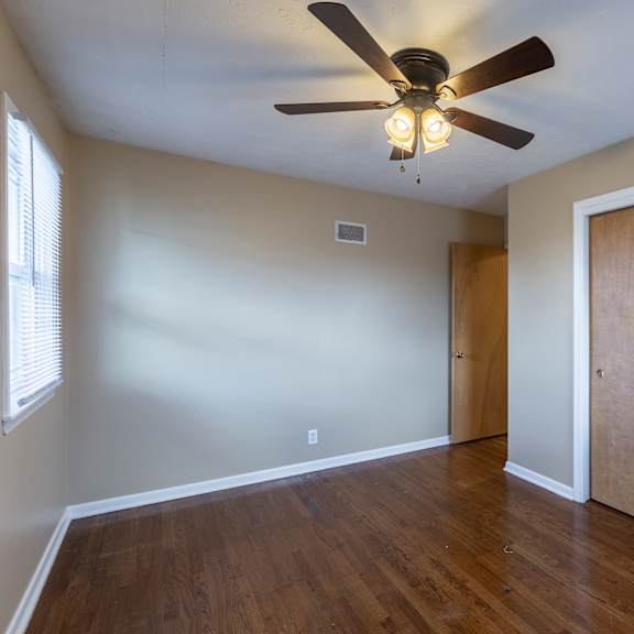 a room with a ceiling fan and wooden floors.