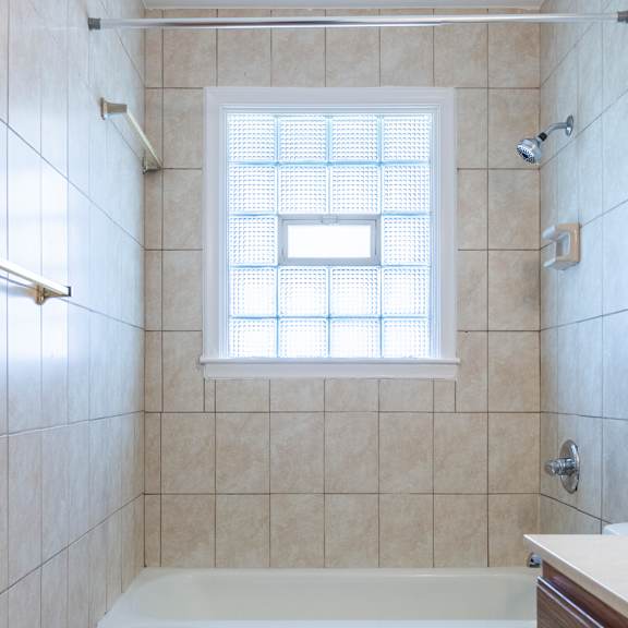 a white toilet sits next to a bathtub in a tiled bathroom.
