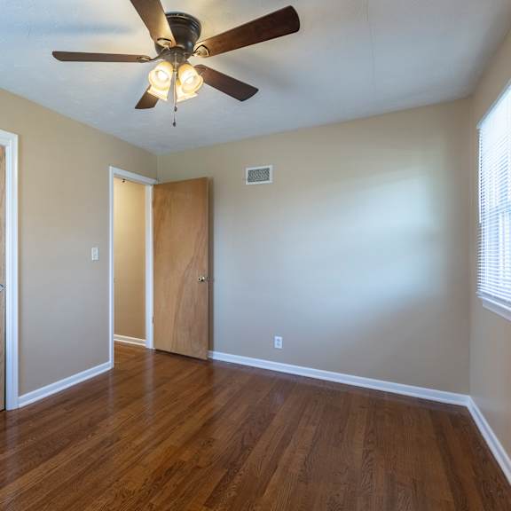 a room with a ceiling fan and wooden floors.