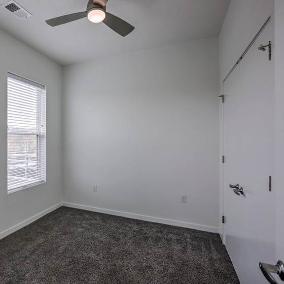 a room with a ceiling fan and carpeted floor.